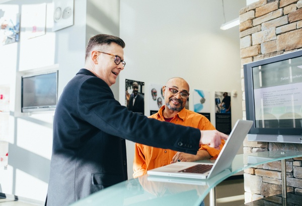 Business owner looking at laptop computer with M&A advisor discussing selling their business